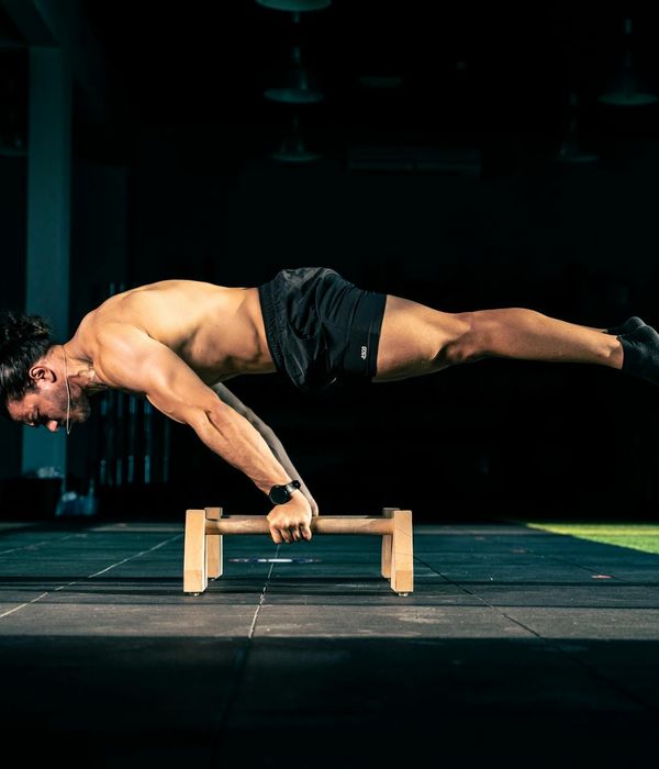 Man performing a controlled strength exercise in a modern, dark gym.